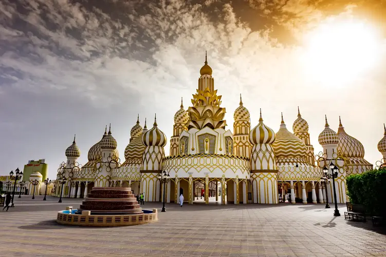 Krievijas paviljons "Global Village" parkā Dubaijā - liela ēka ar baltiem un zelta krāsas rakstainiem sīpolveida kupoliem plašā laukumā.